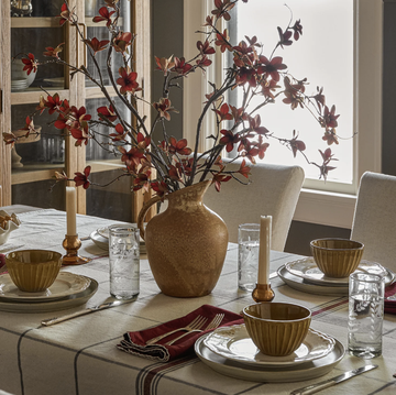 joanna gaines magnolia fall collection, dining room with a vase of faux flowers, red napkins and neutral toned plates