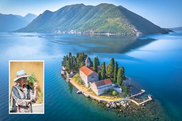 island featuring a historic stone building surrounded by trees and water