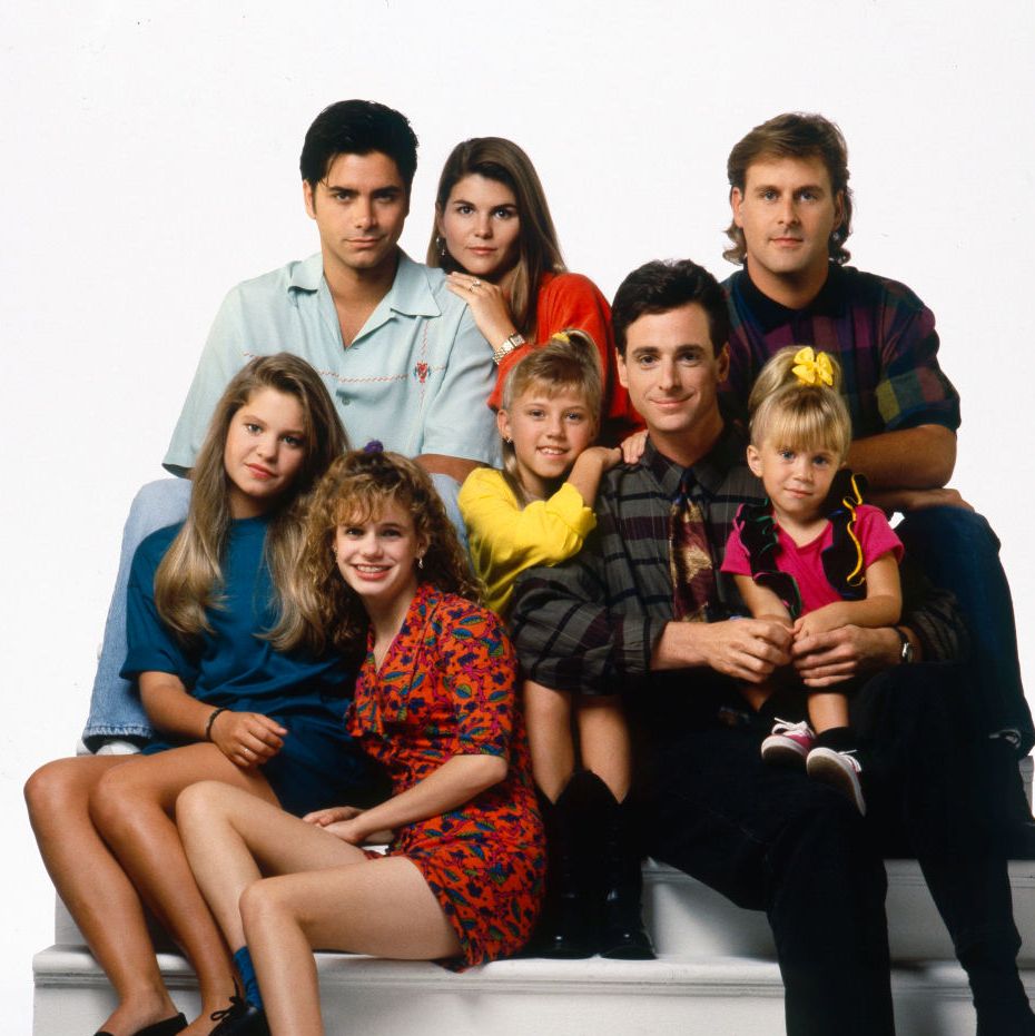 john stamos sitting for a cast photo with the actors of full house