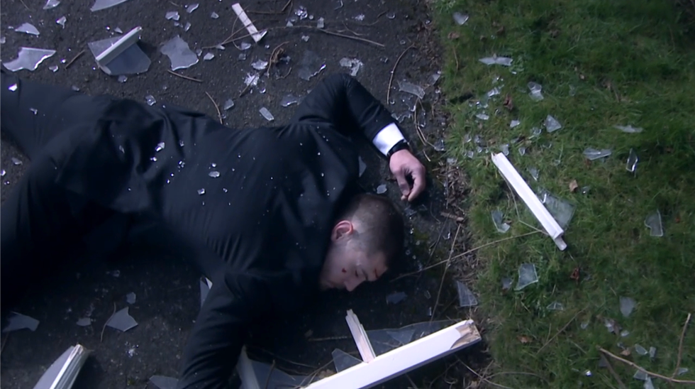 joe tate lying on the pavement after being pushed out of a window, emmerdale