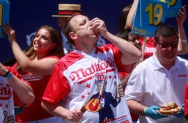 joey chestnut stuffing his mouth with hot dogs during an eating competition