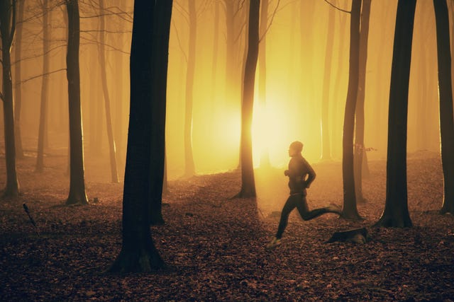 Jogger at sunrise in misty forest