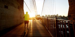 jogger in bright jacket running into the sunset on brooklyn bridge