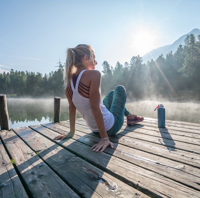 jogging woman relaxing on lake pier at sunrise enjoying freshness from nature
