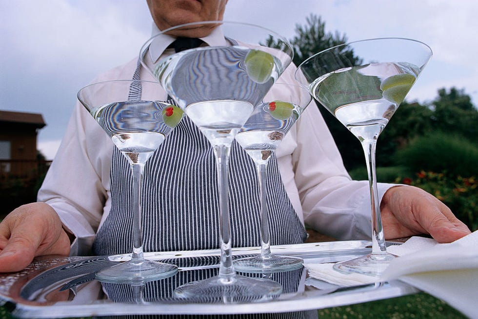 butler carrying a tray of martinis outside