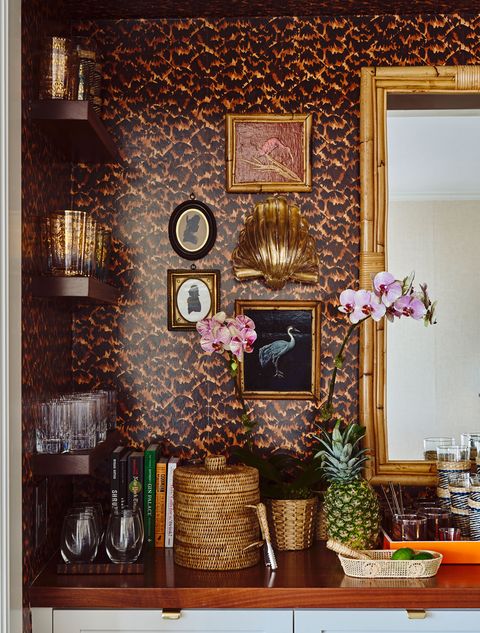 Eclectic home bar with rattan, gilt, tortoise wallpaper, and accessories