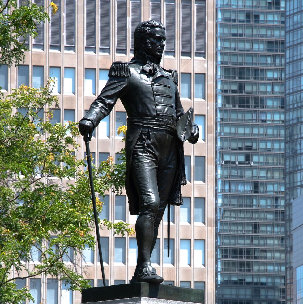 a statue of a man holding a hat and a cane
