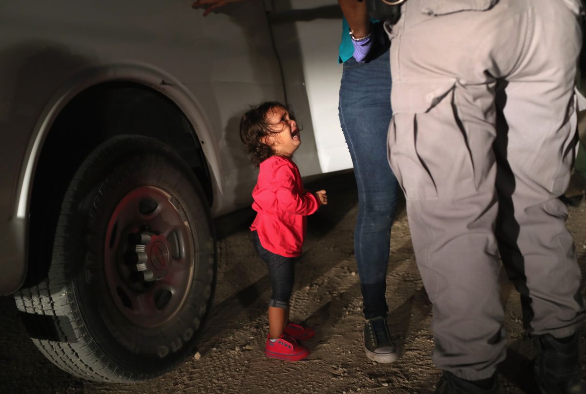 A two-year-old Honduran asylum seeker cries as her mother is searched and detained near the U.S.-Mexico border in McAllen, Texas.