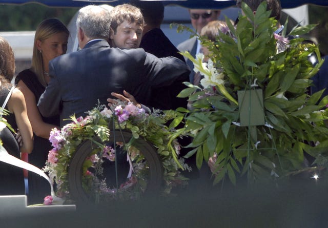 burke ramsey hugs a man as floral arrangements rest in the foreground