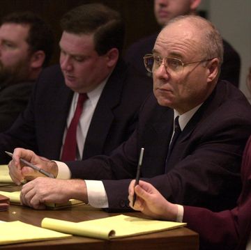 three men and a woman sitting at a table in court and taking notes