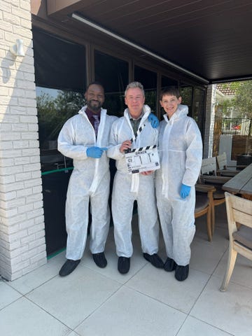 three individuals in protective suits with a clapperboard