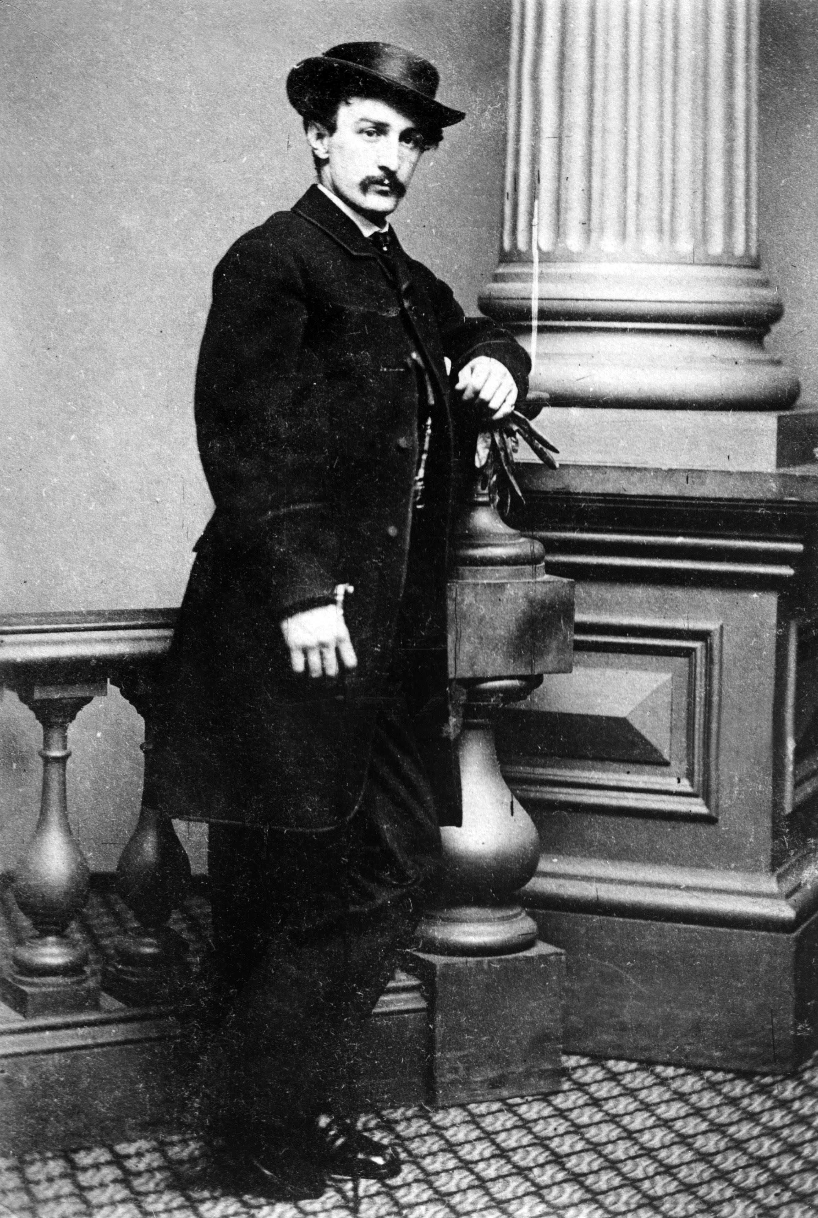 president abraham lincoln assassin john wilkes booth stands for a hpoto wearing a hat and coat