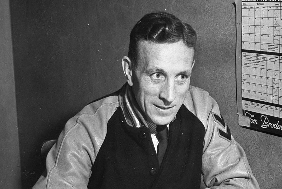 a black and white photo of john wooden wearing a sports jacket