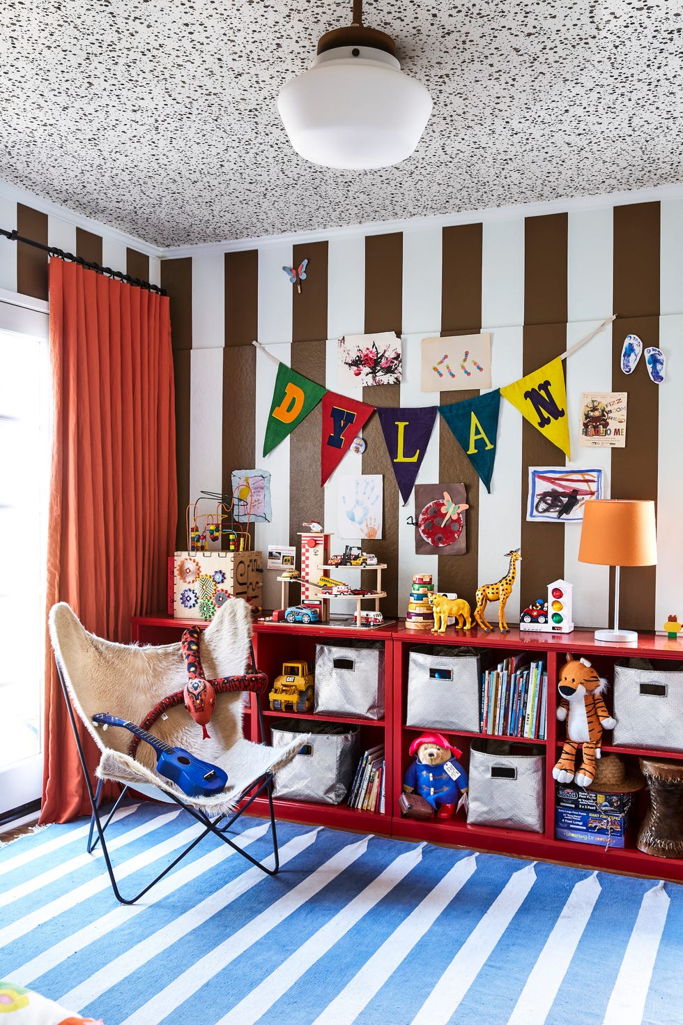 a kids room with brown and white striped walls and red shelves
