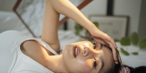 jonge vrouw ligt op bed met haar hoofd in de zon