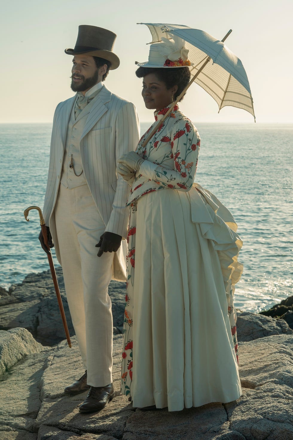 couple in vintage attire standing on a rocky shoreline