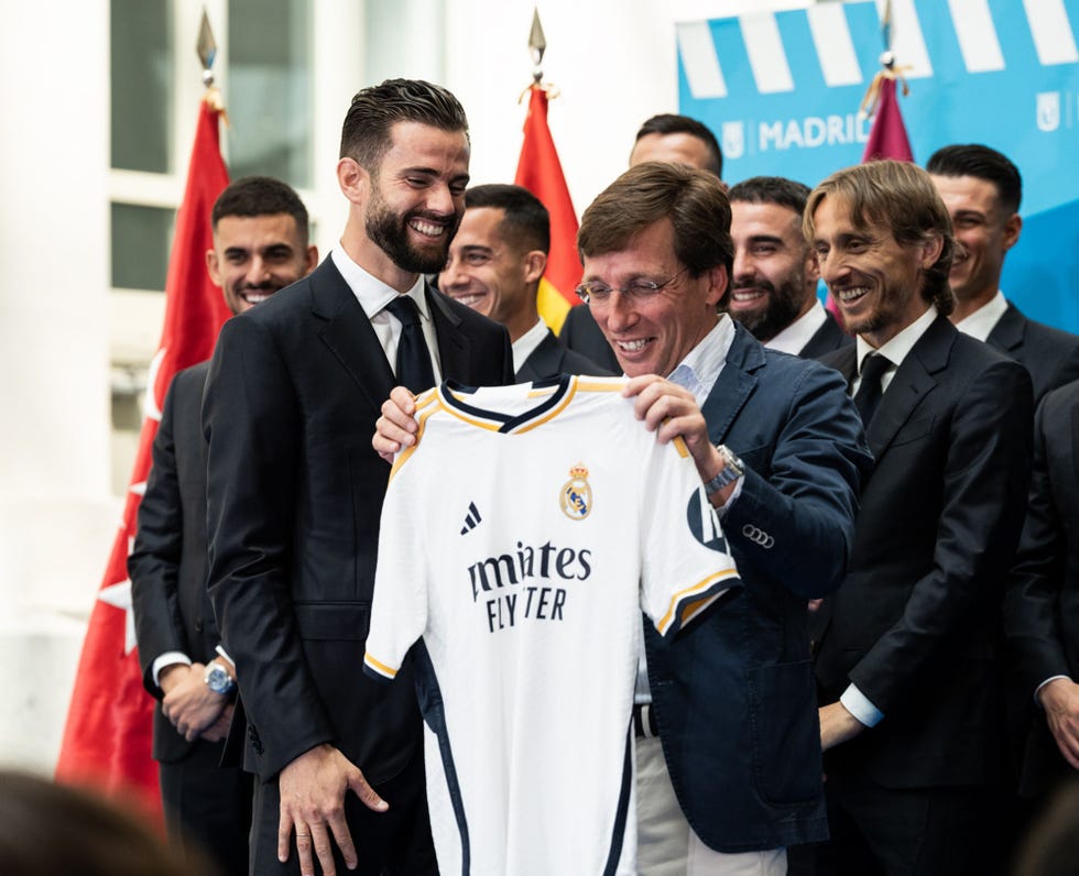 el alcalde de madrid posa con los jugadores del equipo blanco que le regalan una camiseta del equipo