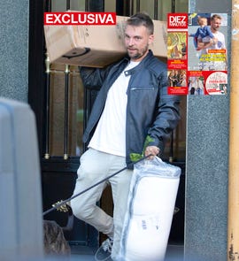 el hijo de carmen borrego sale de un portal con una caja y un colchon