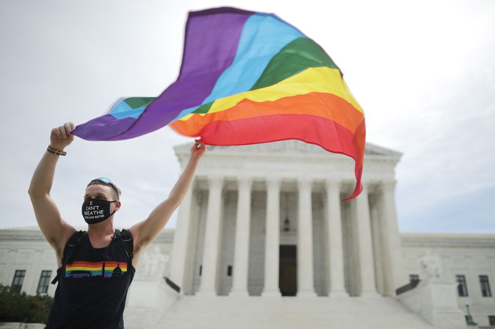 joseph fons holding a pride flag in front of the us supreme court building after the court ruled that lgbtq people can not be disciplined or fired based on their sexual orientation