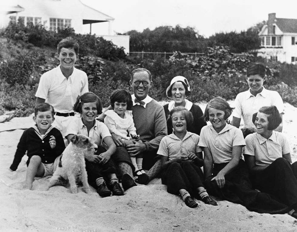 the kennedy family sit on the beach and smile for a picture