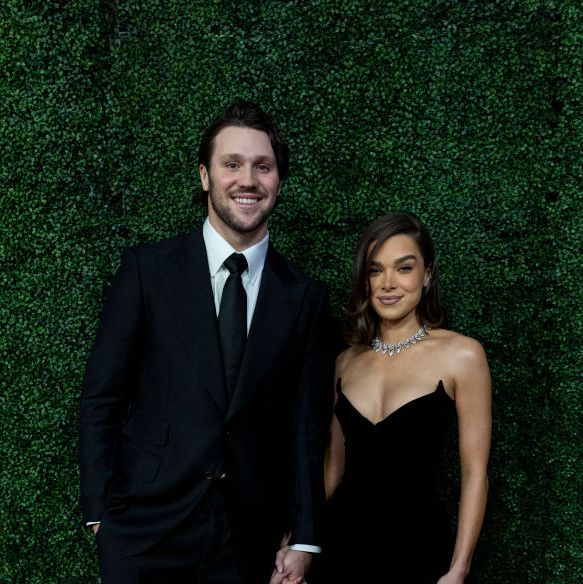 a man and a woman both wearing formal black attire hold hands and smile at the camera