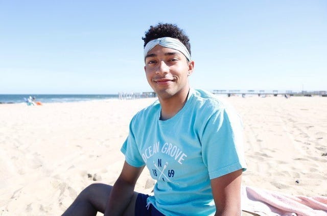 person sitting on the beach in casual attire with ocean in the background