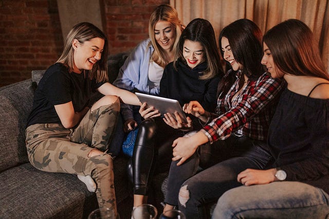 mujeres jóvenes alrededor de una tablet en una casa
