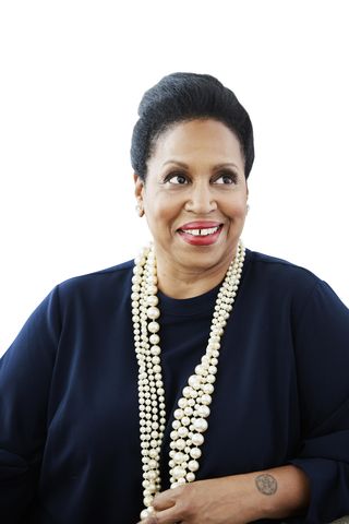 a photo of a black woman smiling and wearing several strands of pearls