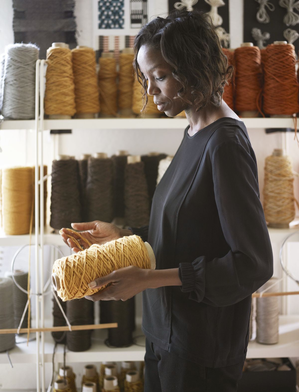 art director of merida sylvie johnson inspects a spool of golden yarn in a studio