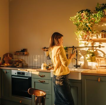 joyful woman talking on cellphone while preparing salad at home kitchen
