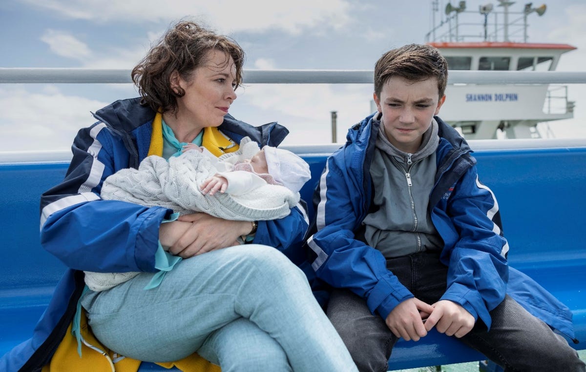 olivia colman in joyride, sat on a bench next to charlie reid and holding a baby