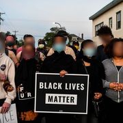 protesters hold a black lives matter sign their faces are blurred