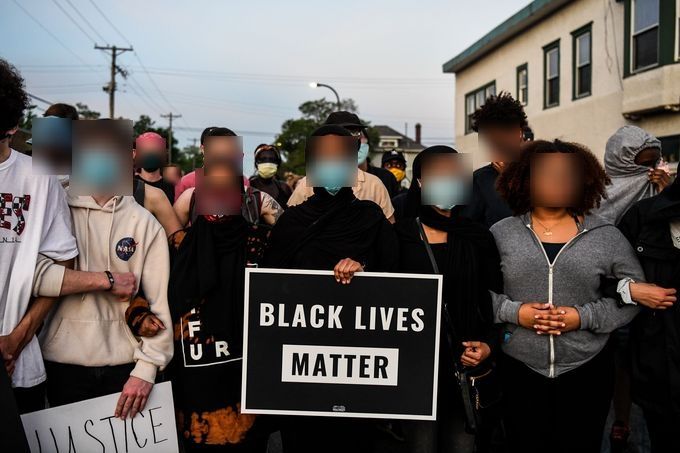 protesters hold a black lives matter sign their faces are blurred
