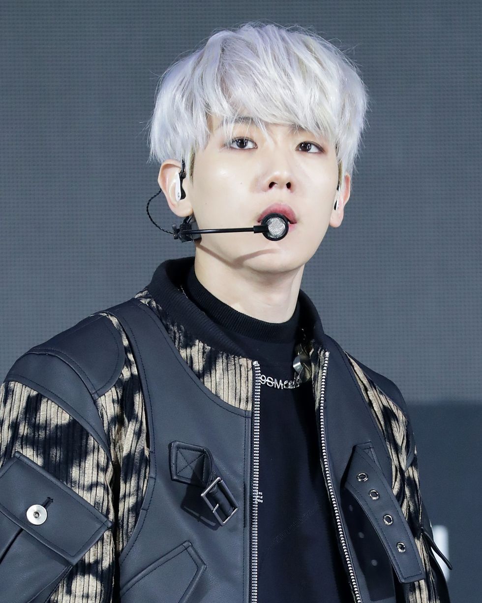 a person with white hair and a black jacket with a microphone in front of him