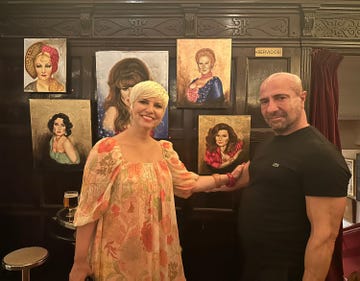 juan pacheco posa con pasion vega frente a sus cuadros de la serie las chicas de la cuarentena