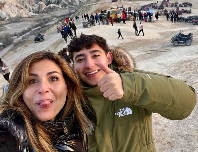 a man and woman taking a selfie in front of a beach