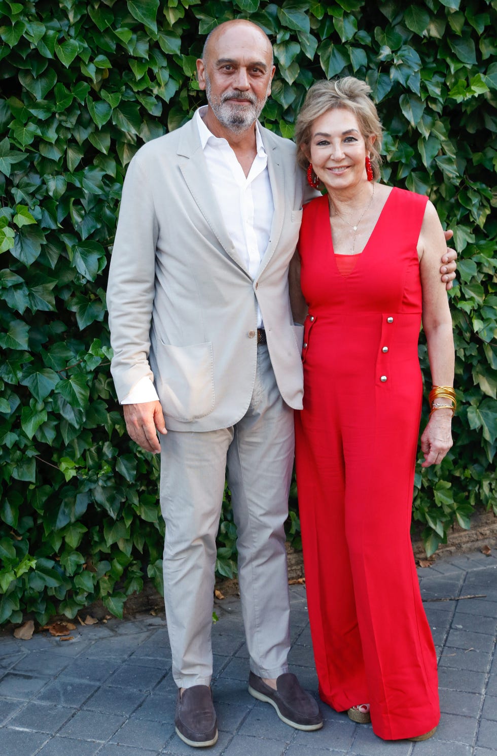 la periodista, de rojo, posa con su esposo con traje beige