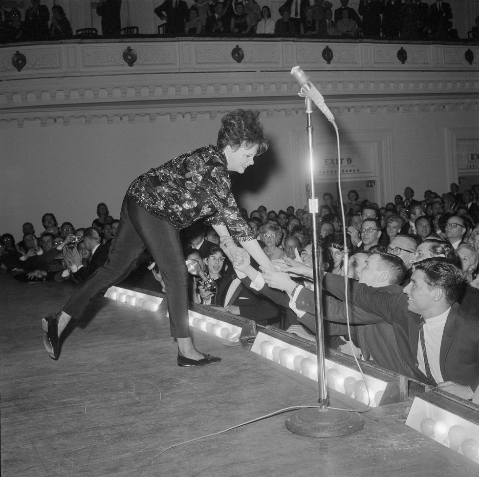 original caption judy garland leans over the footlights to greet some of her enthusiastic fans during her concert at carnegie hall judy thrilled a standing room only audience by her performance and drew several ovations during the evening