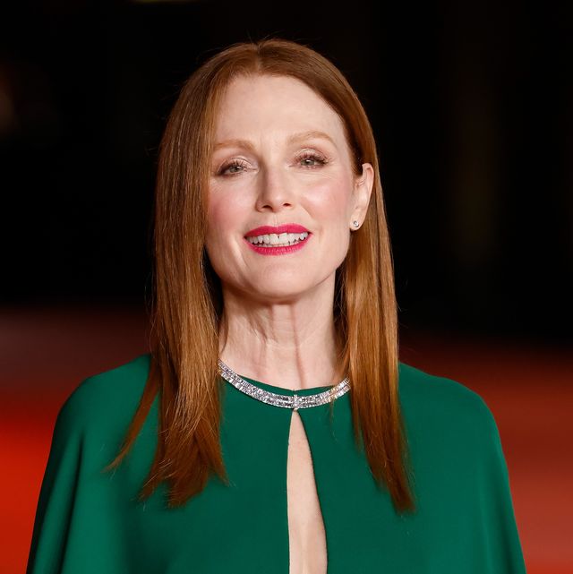 julianne moore smiles at the camera, she wears a green gown and diamond necklace and stands on a red carpet