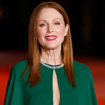 julianne moore smiles at the camera, she wears a green gown and diamond necklace and stands on a red carpet