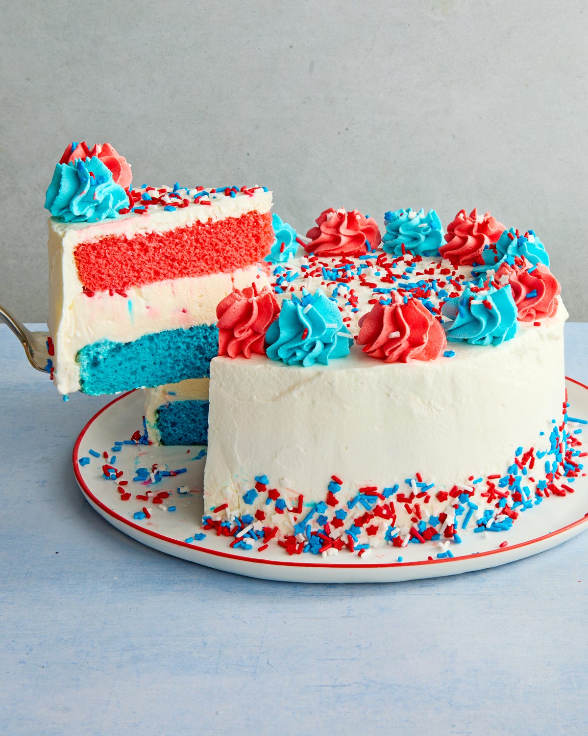 ice cream cake layered with blue, white, and red, topped with blue and white dollops of icing and sprinkles