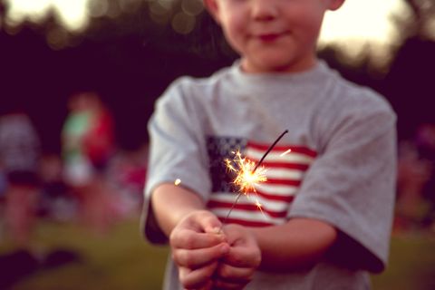 little boy in an american flag t shirt holding sparkler