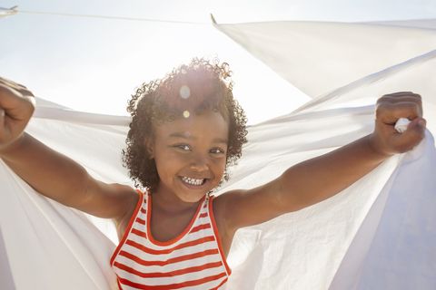 young girl smiling, holding white sheet