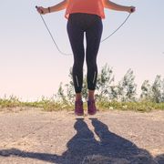 girl in sportswear and sneakers jumping with a skipping rope on in the summer of the sea background, toned image