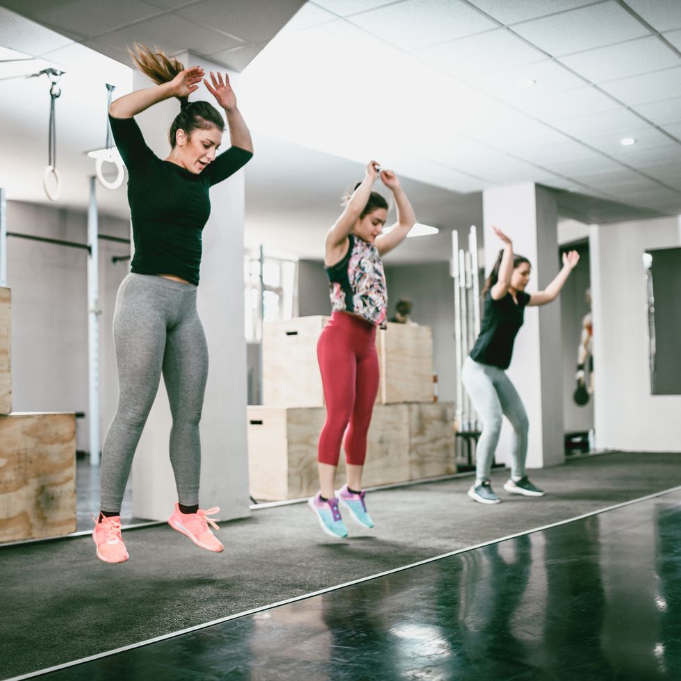 three women doing jumping jacks in the gym