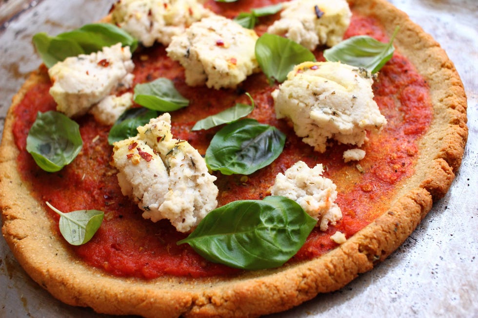 gluten free chickpea flour pizza crust topped with tomato sauce, peanut "ricotta" cheese, and basil