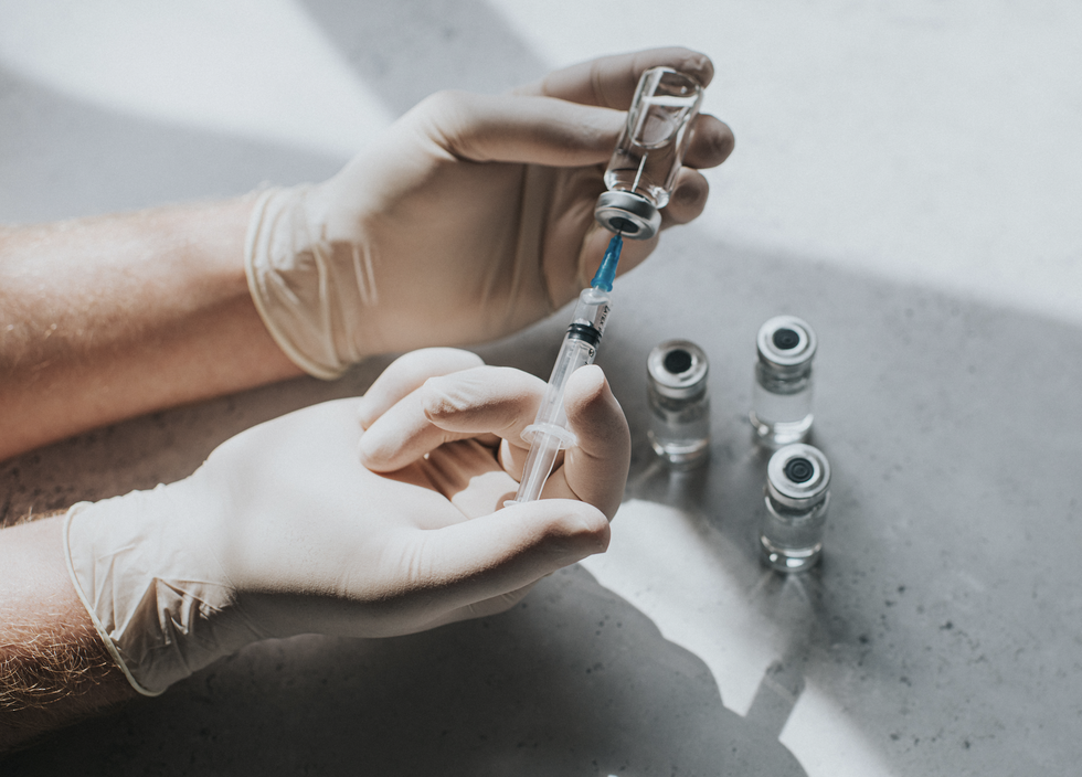 close up of hands holding a syringe preparing vaccines
