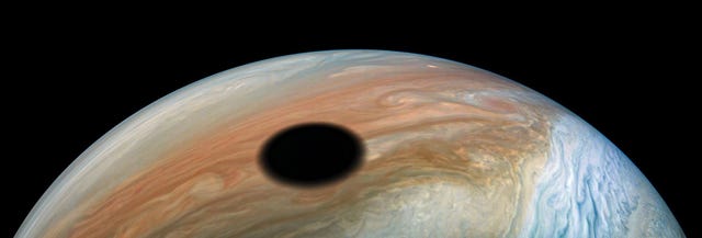 In deze opname van de NASAsonde Juno is te zien hoe Jupiters maan Io  een wereld van vulkanisme die elke 42 uur nmaal om de reuzenplaneet draait  zijn schaduw op het Joviaanse wolkendek werpt