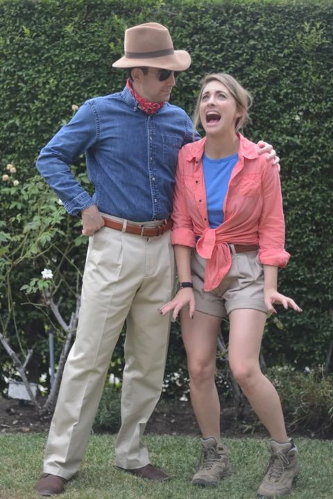 a couple dressed as grant and ellie from jurassic park standing outside near bushes the costume idea is a good housekeeping pick for best 90s halloween costumes