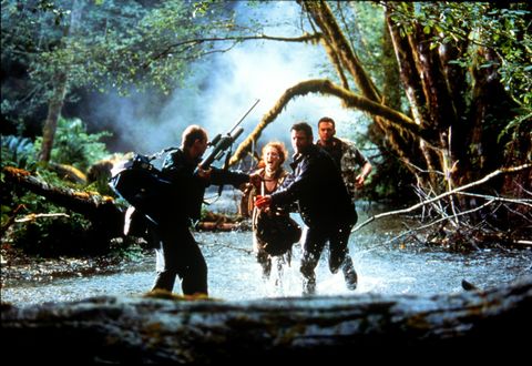 ian malcolm and sarah harding join others as they run through water to escape dinosaurs in a scene from the lost world jurassic park, the second film if you want to watch the jurassic park movies in order